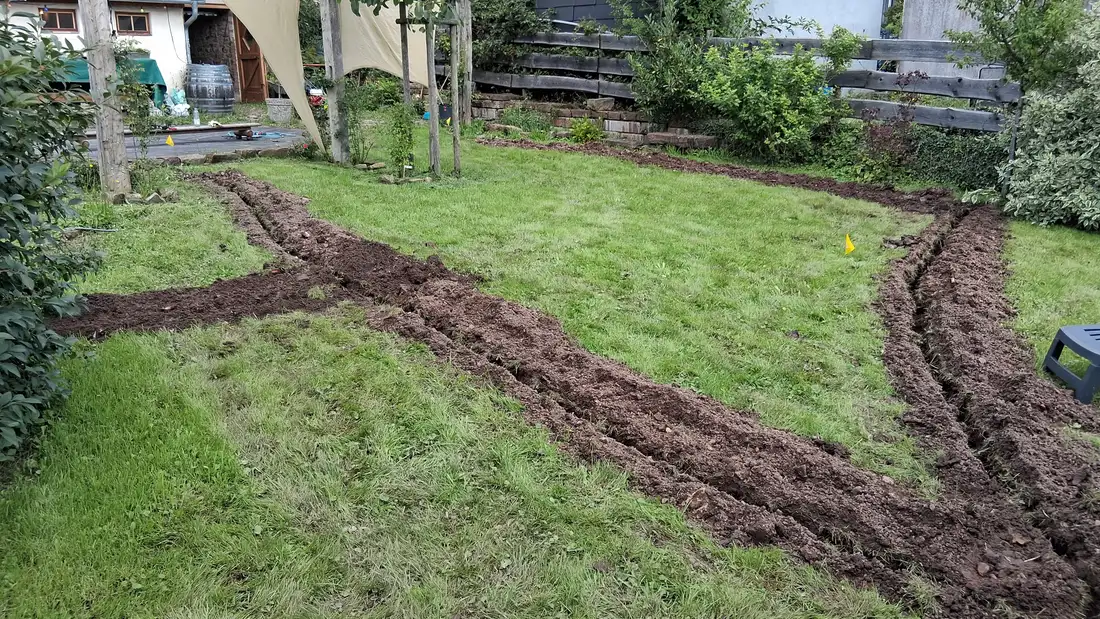 Gefräste Leitungsgräben ziehen sich durch einen Rasen mit Bäumen