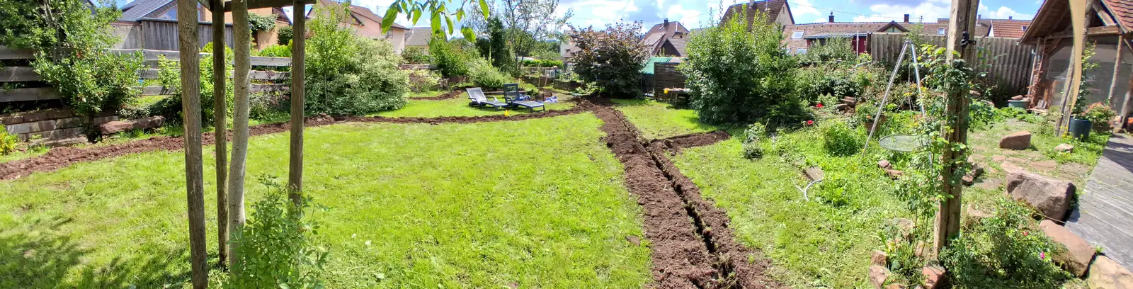 Panorama eines Gartens mit frisch gefrästen Leitungsgräben im Rasen