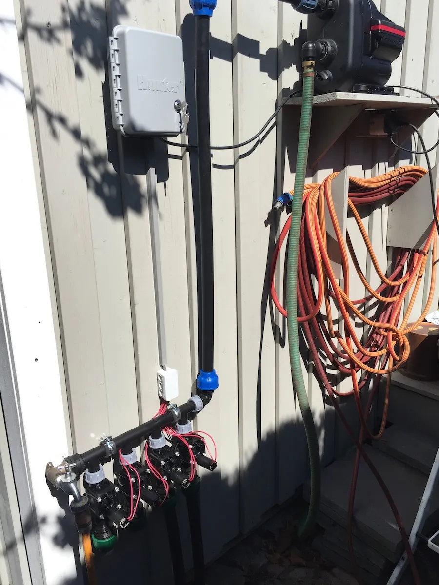 Verteiler mit Magnetventilen und Anschlussleitungen an einer Hauswand